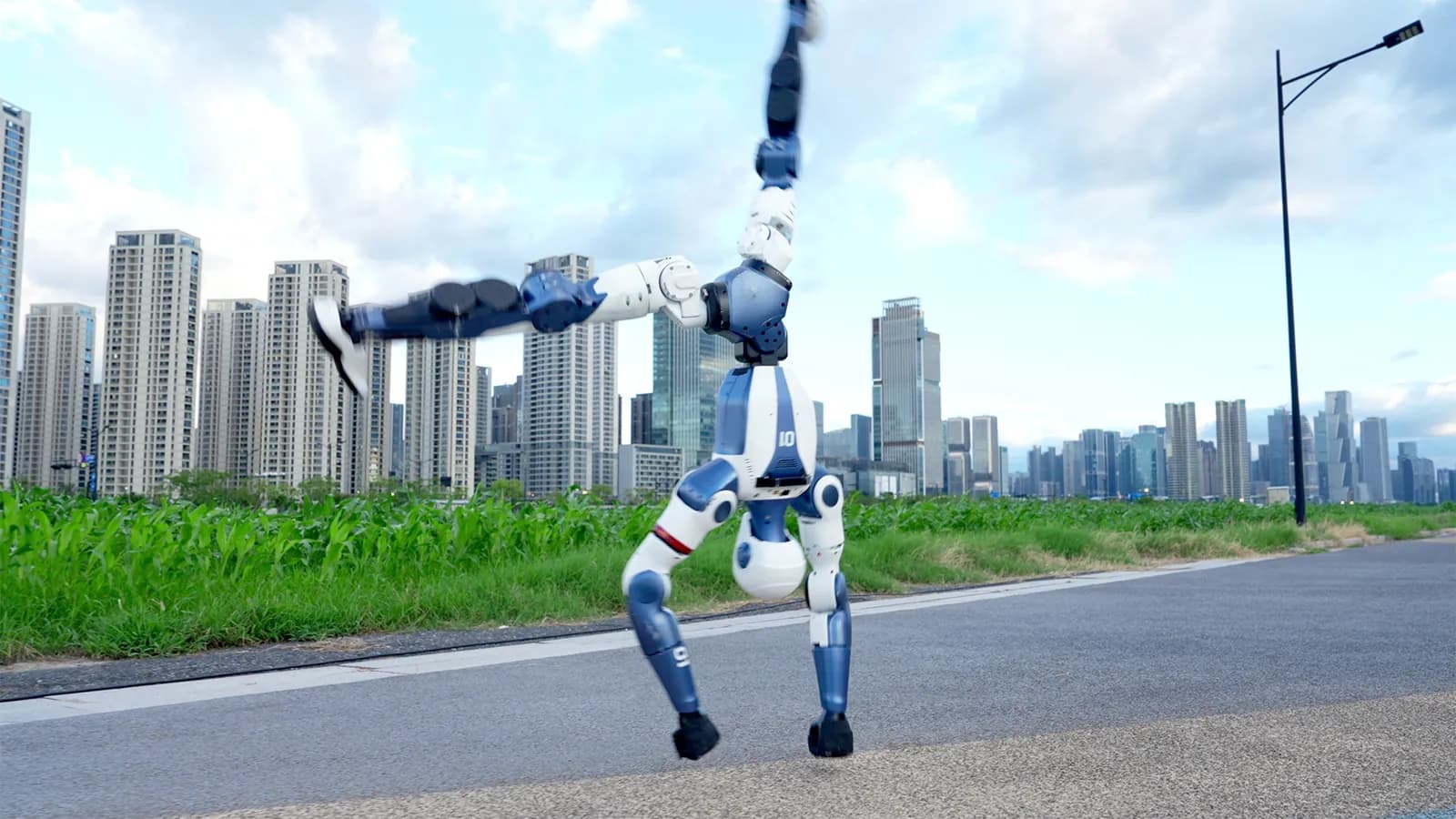 The Unitree R1 robot standing on its hands on asphalt, with apartment blocks in the background