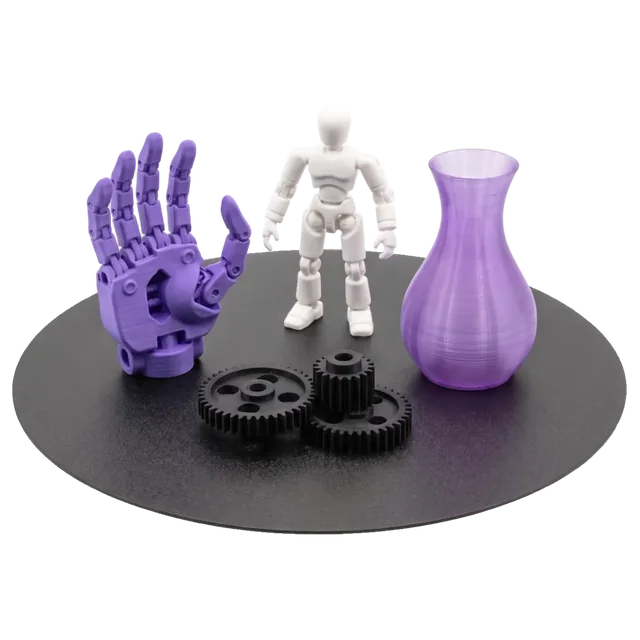3D printed parts on the printer build plate: a violet robotic hand, a figurine, gears and a vase
